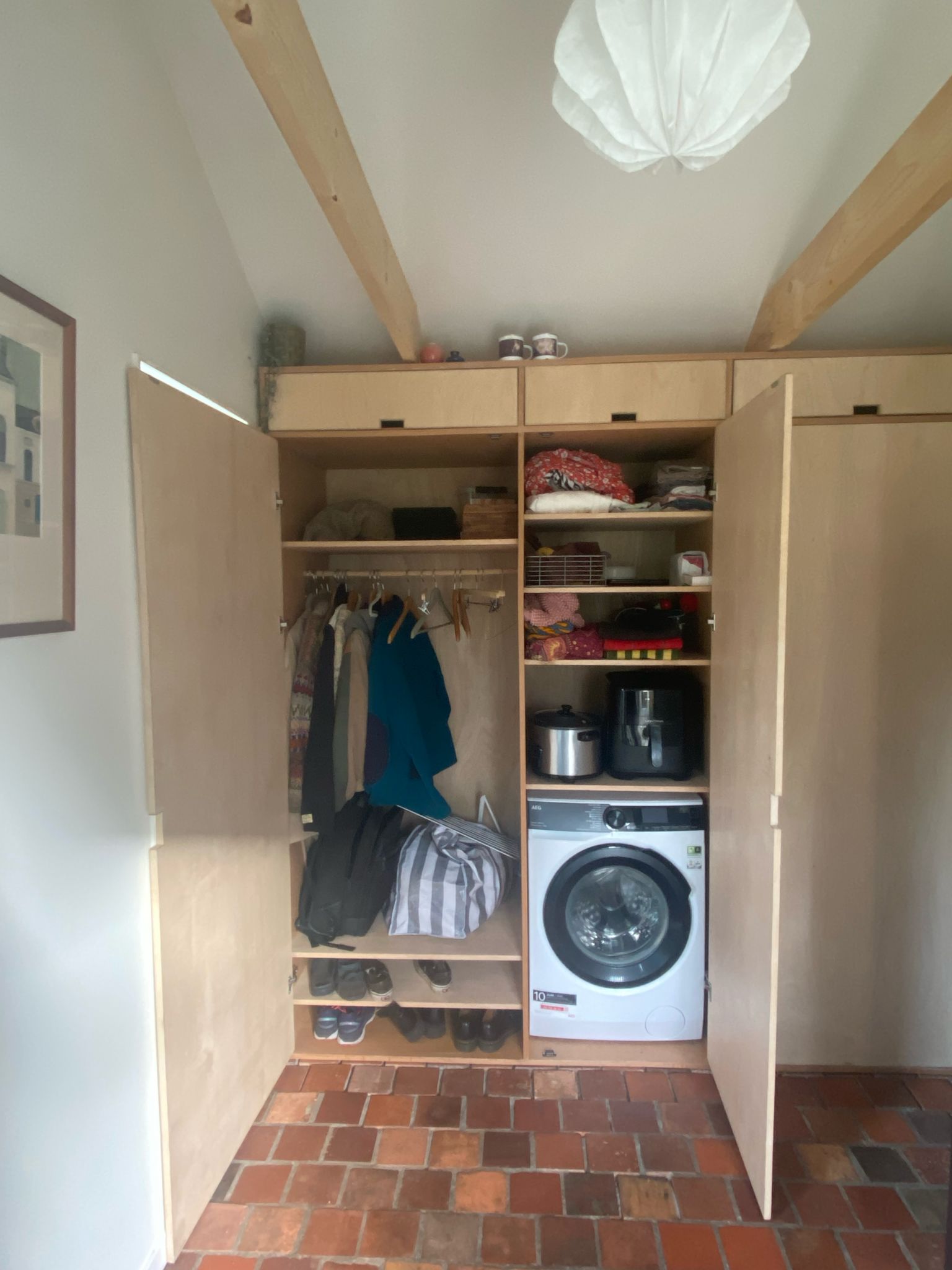 Inbouwkast op maat in bijkeuken met open deuren en wasmachine